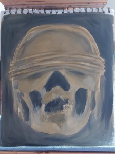 canvas sketchpad on a wooden easel with a loose sketch of a human skull wearing a blindfold. The colour palette is yellow ochre, ivory black and titanium white